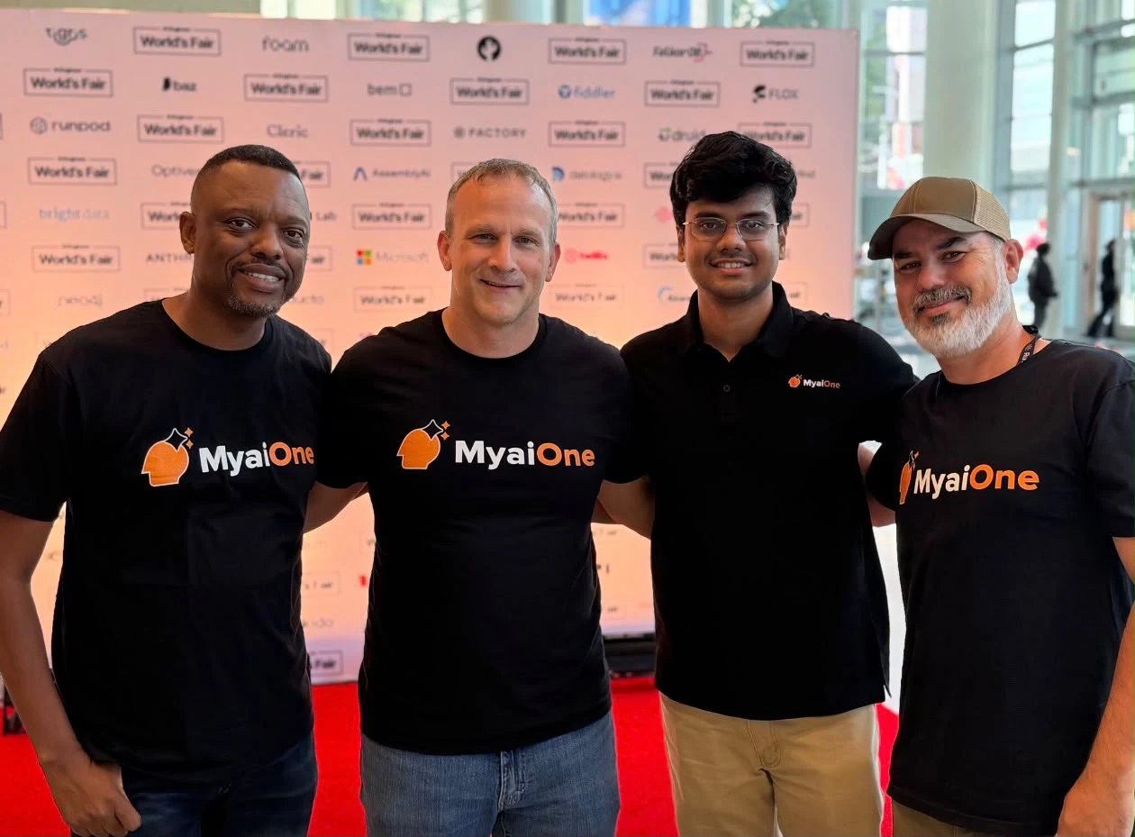 Four event attendees in MyaiOne shirts standing together.